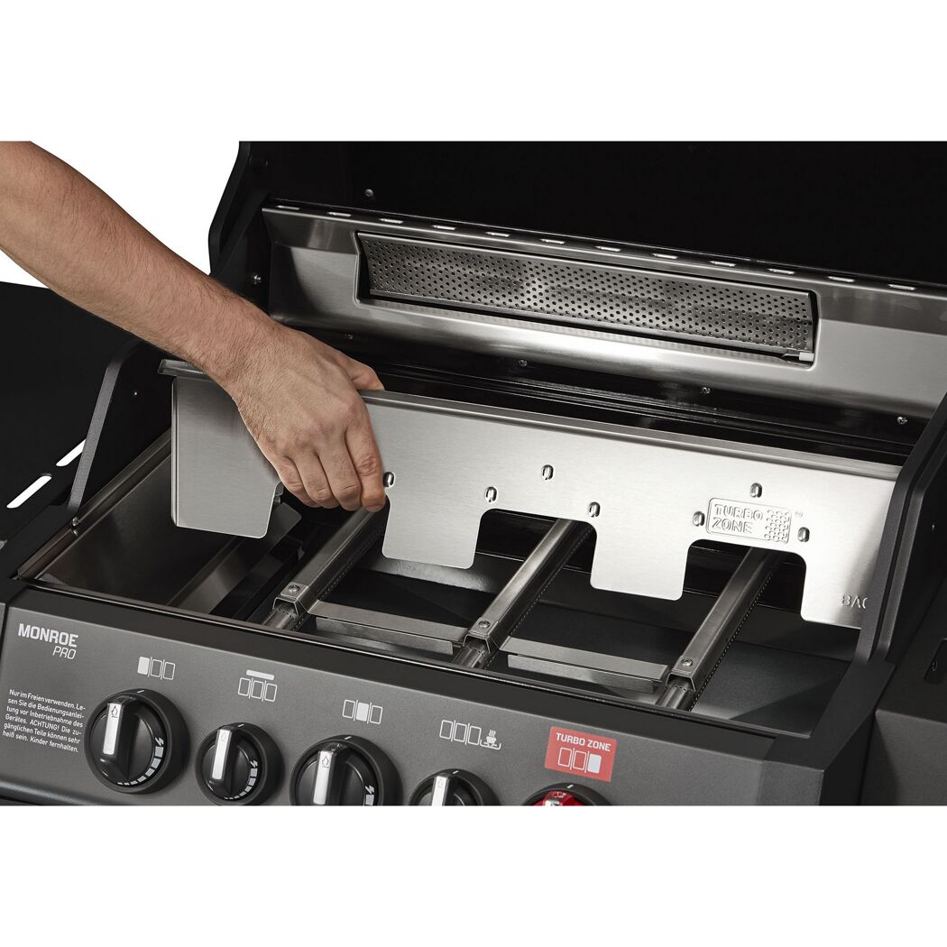 Person reinigt einen Gasgrill