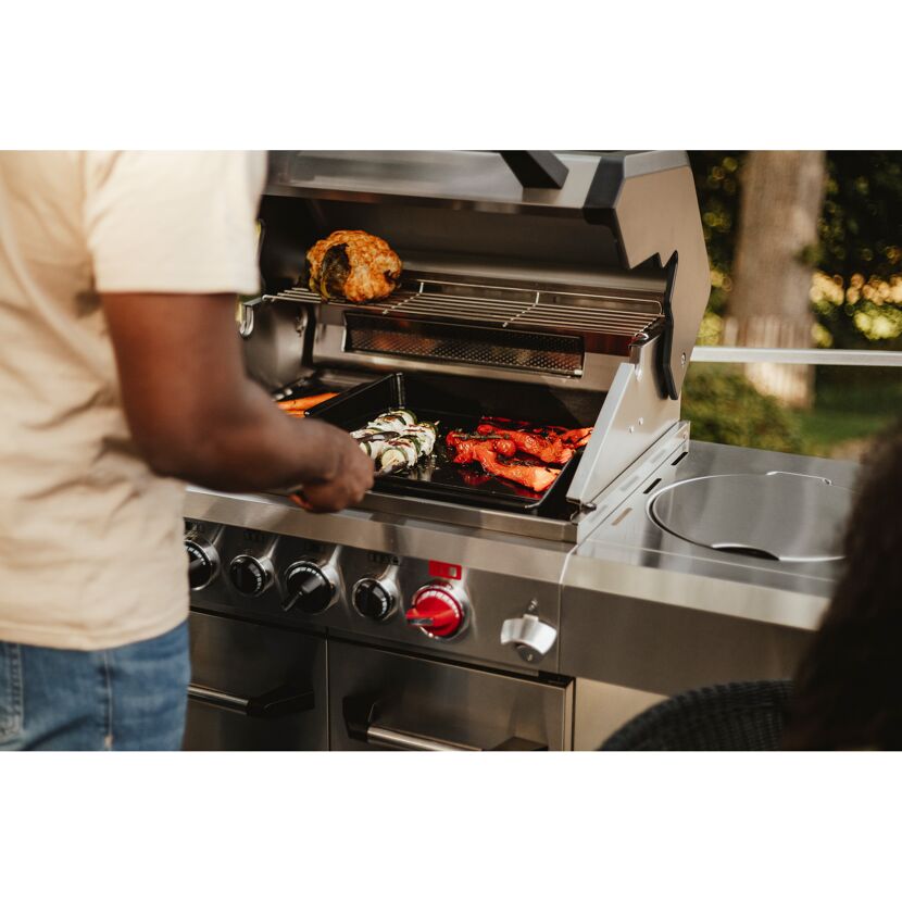 Person grillt Gemüse auf einem Gasgrill