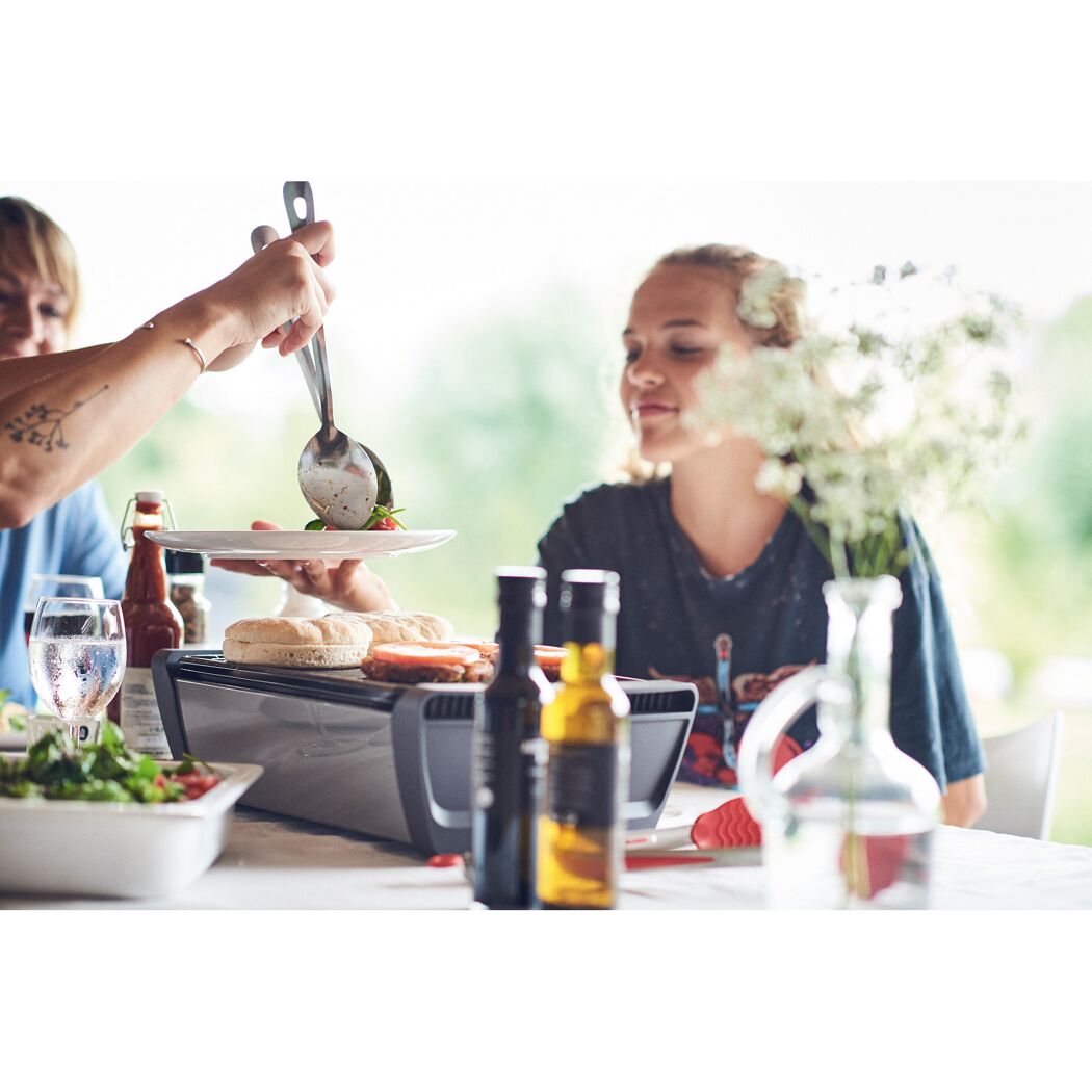 Person serviert Essen von einem Tischgrill