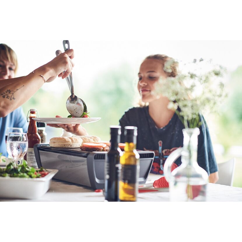 Person serviert Essen von einem Tischgrill