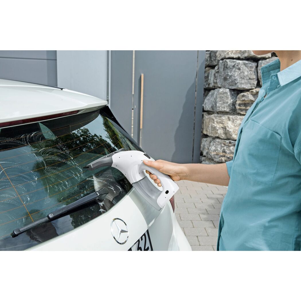 Person reinigt Autoscheibe mit Fenstersauger