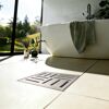 Geschlitzter quadratischer Bodenablauf im hellen Badezimmer.