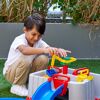 Lachendes Kind spielt mit bunter Wasserbahn.