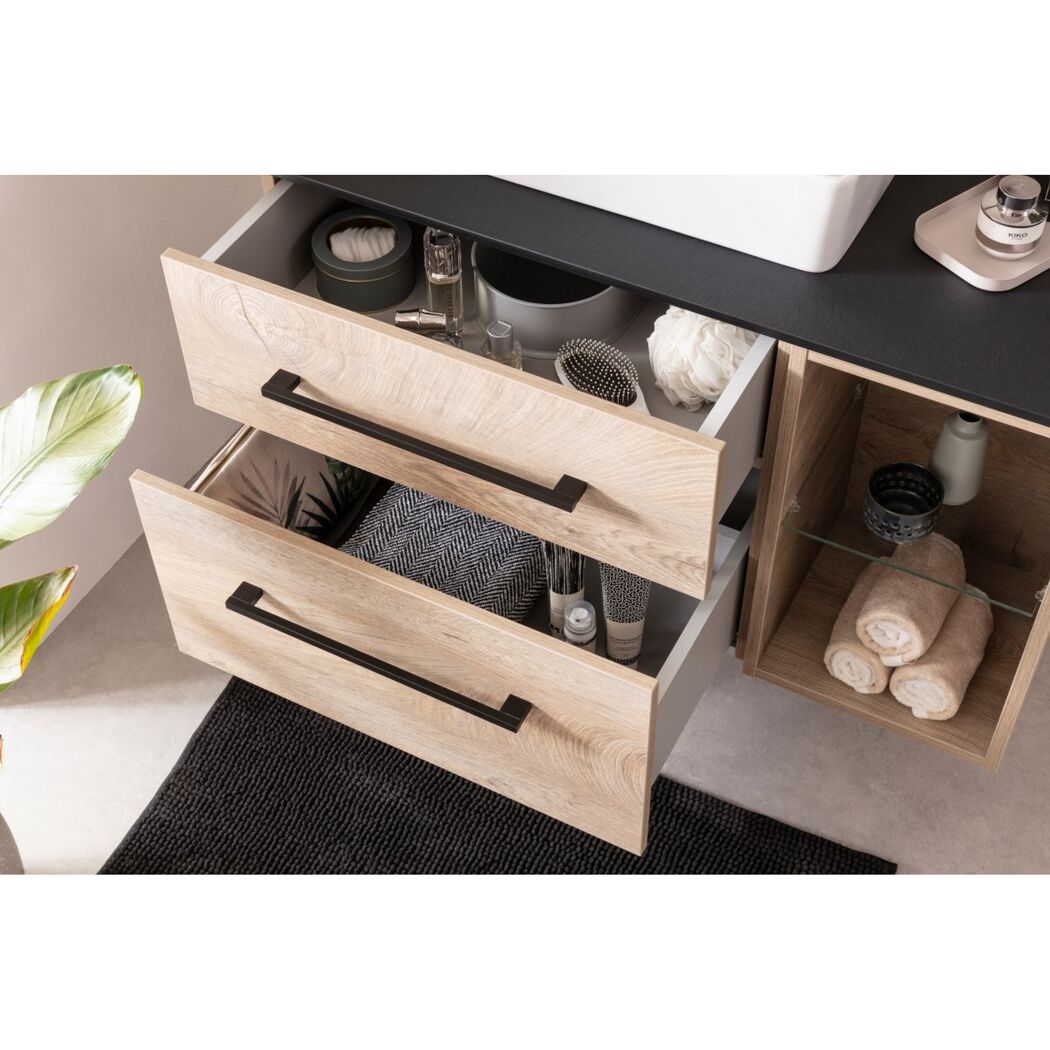 Badschrank mit hellen Holzschubladen und schwarzen Griffleisten.