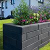 Basaltfarbener Mauerstein 'T-Wall Fine' als Hochbeet mit Blumen.