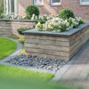 Mauersteine 'T-Wall Linear' muschelkalkfarben im Gartenbeet.