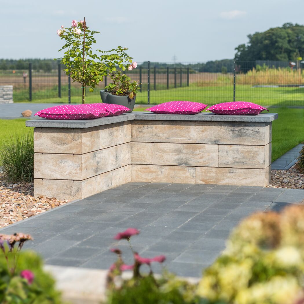 Mauerstein 'T-Wall Linear Maxi' als Gartenmauer mit pinken Kissen