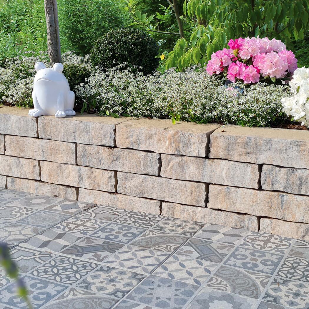 Mauerstein 'T-Wall Castra' als Gartenmauer mit Blumen und Frosch.