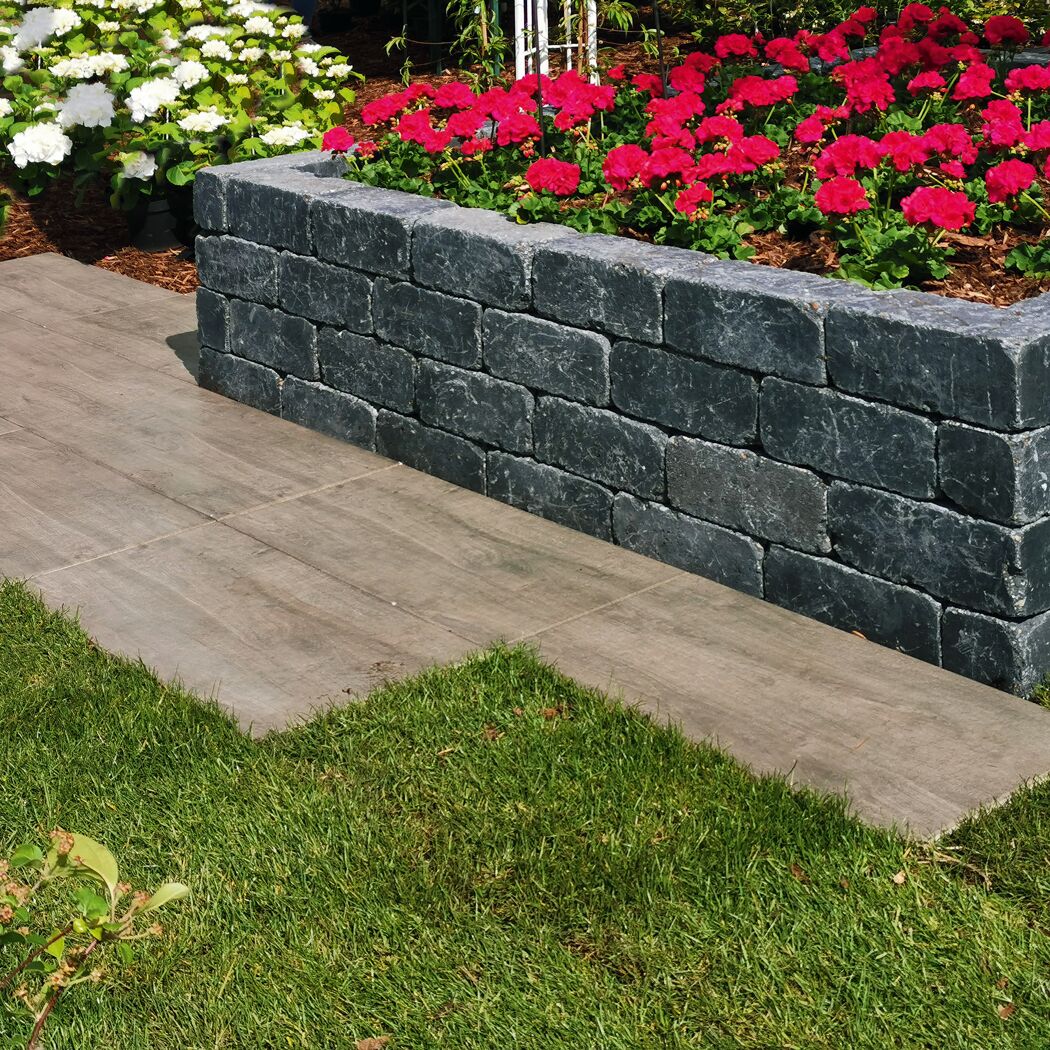 Basaltfarbene T-Wall Mauer als Gartenbegrenzung mit Blumenbeet.