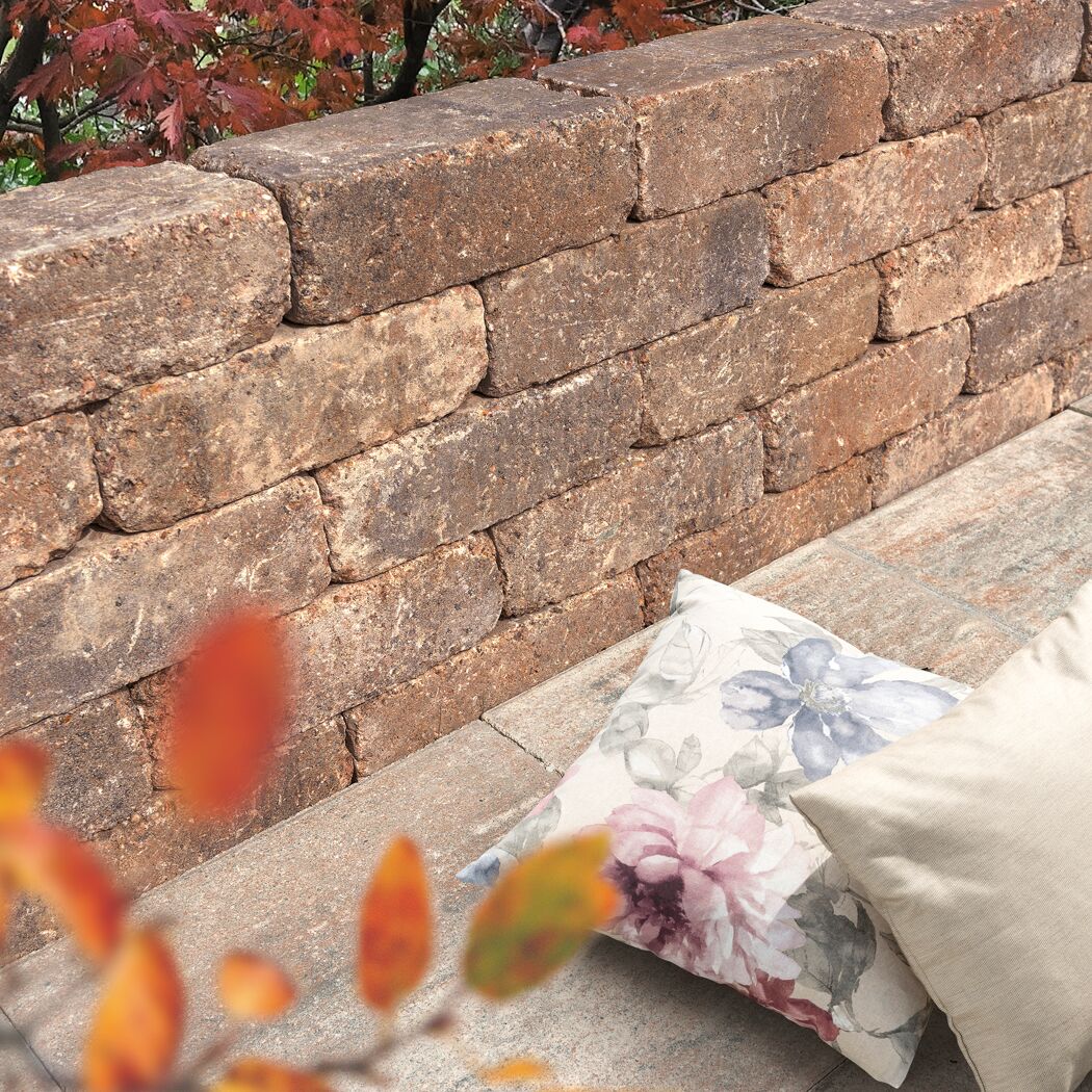 Mauerstein 'T-Wall Aged Midi' mit Kissen und Herbstlaub.