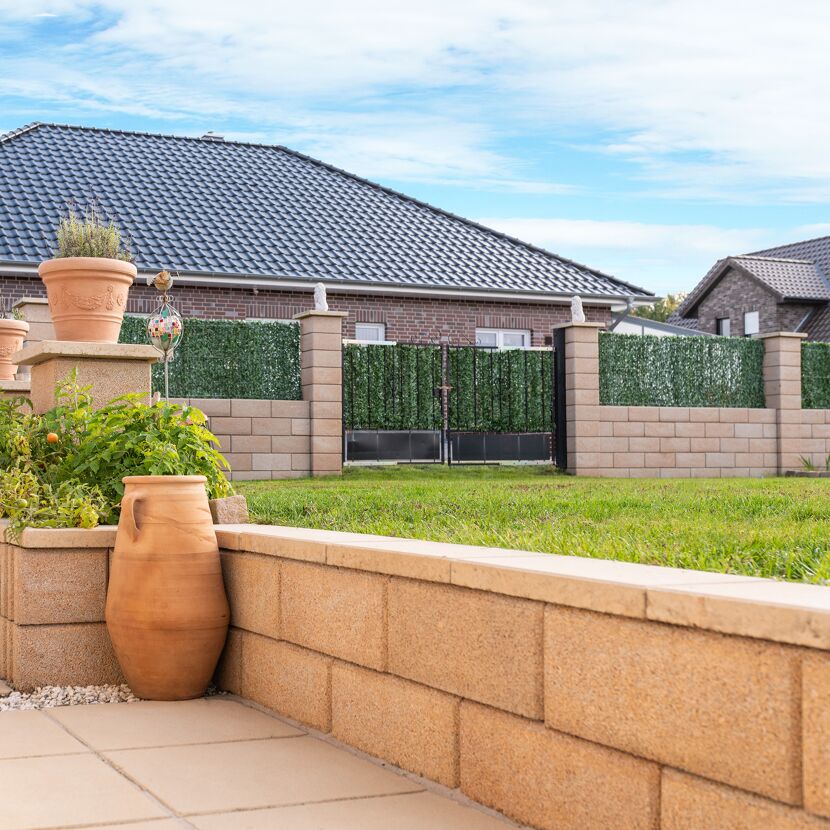 Sandsteinfarbene Abdeckplatte des T-Wall Systems im Garten.