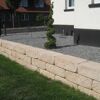Sandsteinfarbene Mauersteine als Gartenbegrenzung mit Rasen.