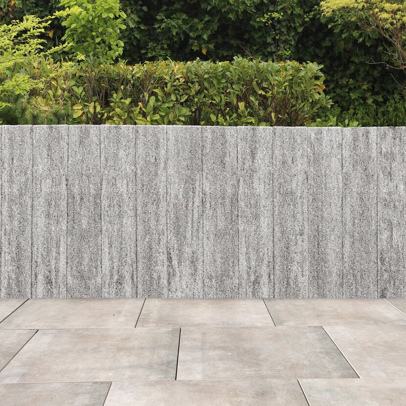 Granitfarbene Palisade 'T-Gravity Shine' mit Pflanzen und Bodenfliesen.