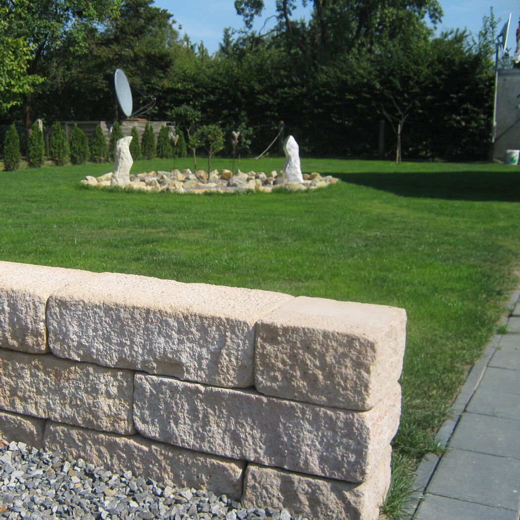 Mauer aus sandsteinfarbenen T-Wall Quarry Big Mauersteinen im Garten.
