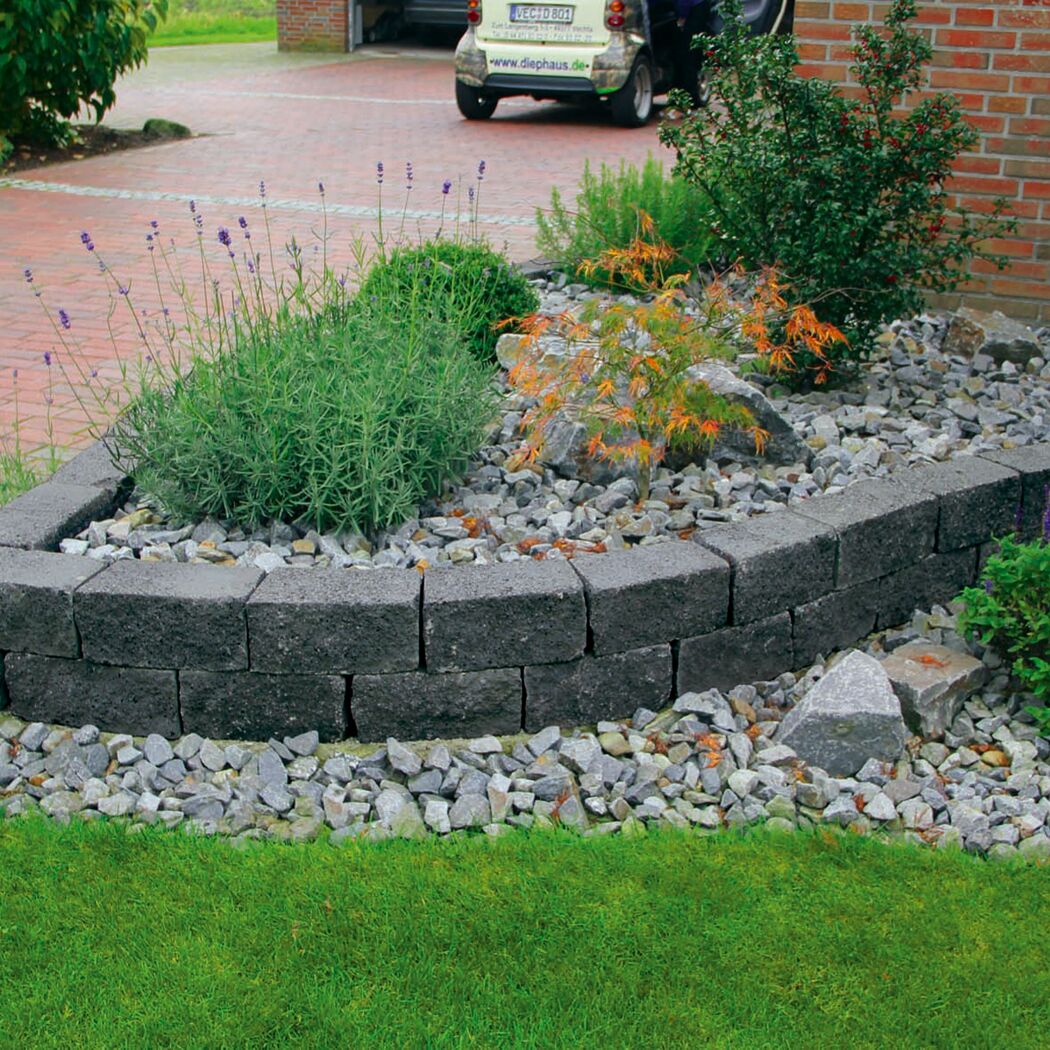 Schwarze Mauersteine T-Wall Quarry Mini als Beetumrandung im Garten.