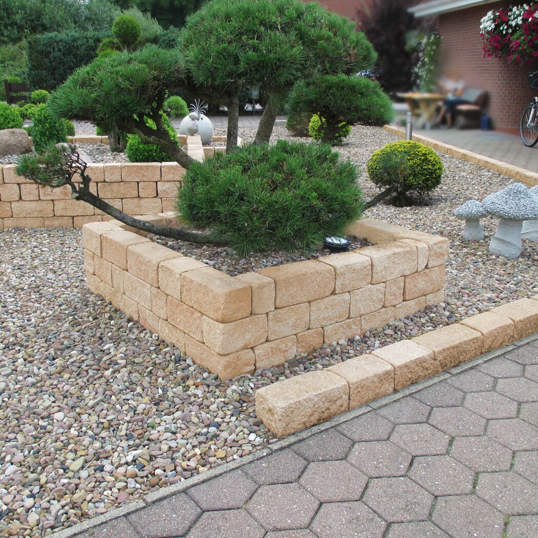 Sandfarbene 'T-Wall Quarry Mini' Mauersteine im Garten als Beetumrandung.