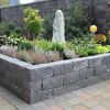 Eingefasstes Blumenbeet mit schwarzen 'T-Wall Quarry' Mauersteinen.