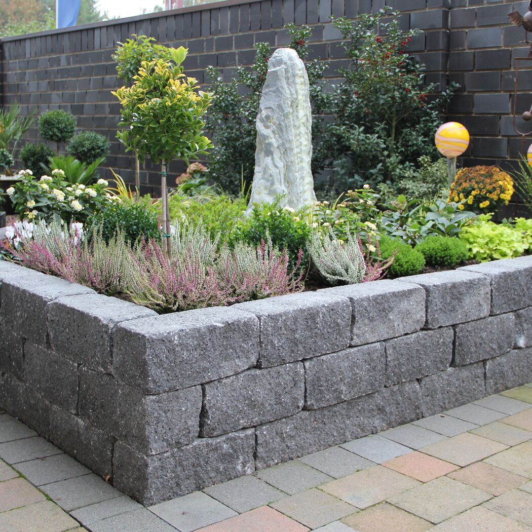 Eingefasstes Blumenbeet mit schwarzen 'T-Wall Quarry' Mauersteinen.