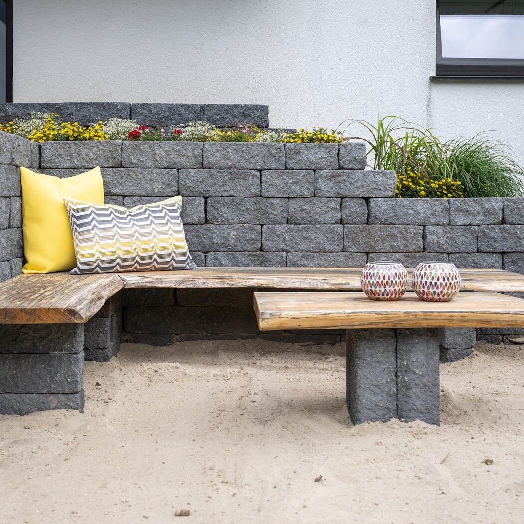 Sitzbank aus T-Wall Quarry Mauersteinen und Holz mit Kissen.
