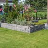 Granitfarbenes Hochbeet aus 'T-Wall Quarry' Mauersteinen mit Rosen.