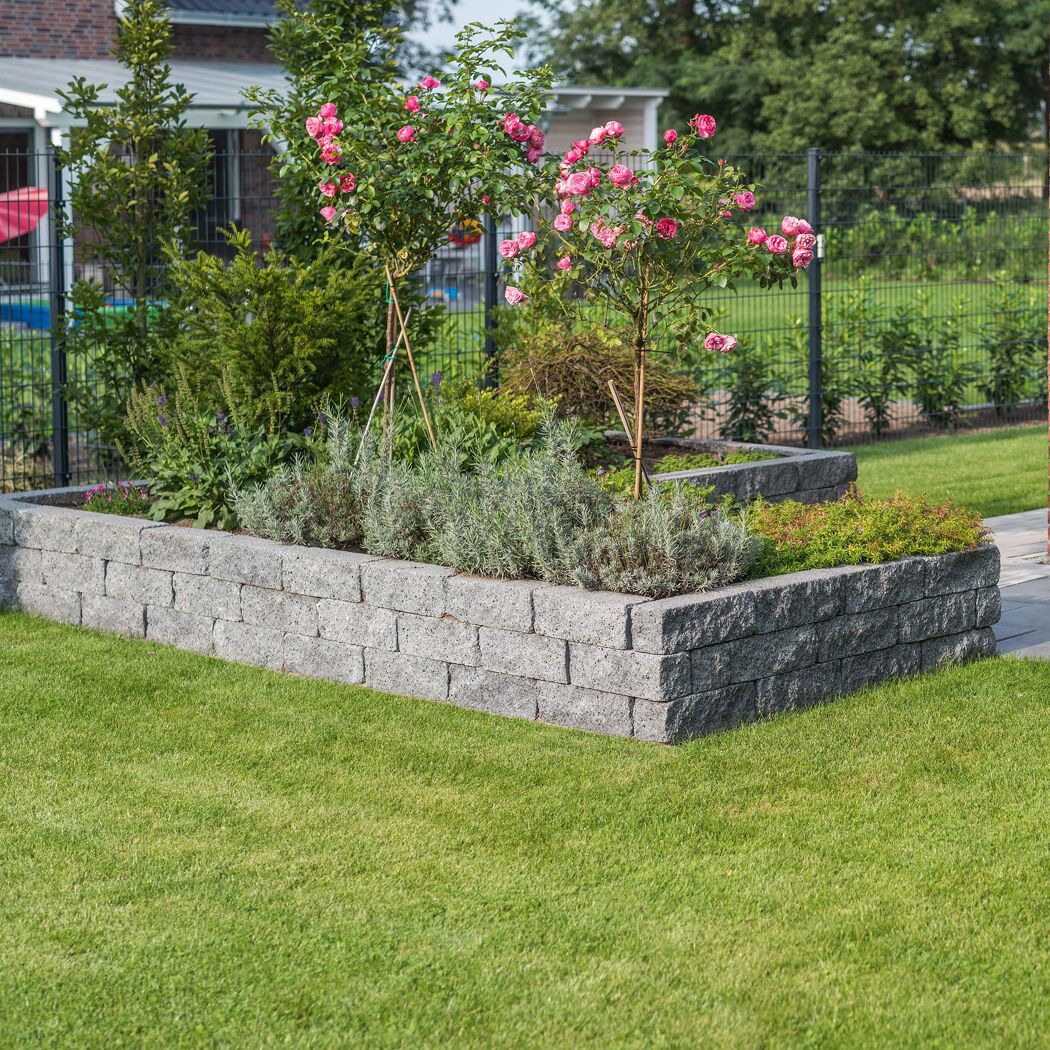 Hochbeet aus granitfarbenen T-Wall Quarry Mauersteinen im Garten.