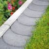 Graue Bordsteineinfassung neben Rasenfläche und Blumen.