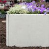 Graue Palisade mit lila und weißen Blumen bepflanzt.