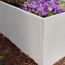 Graue Palisade mit lila Blumen bepflanzt