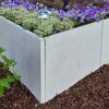 Graue L-Stein-Ecke mit bunten Blumen und Mulch