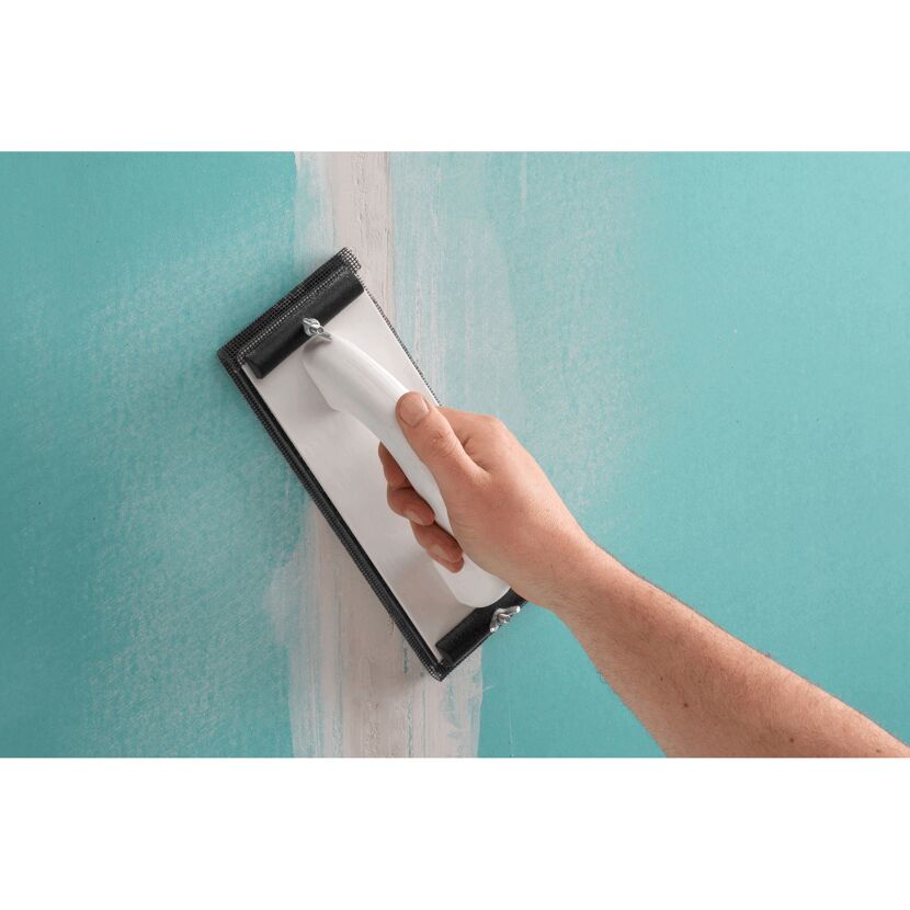 Person schleift mit Schleifgitter eine Wand