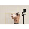 Person bringt mit Kreuzlinienlaser Klebeband an Wand an