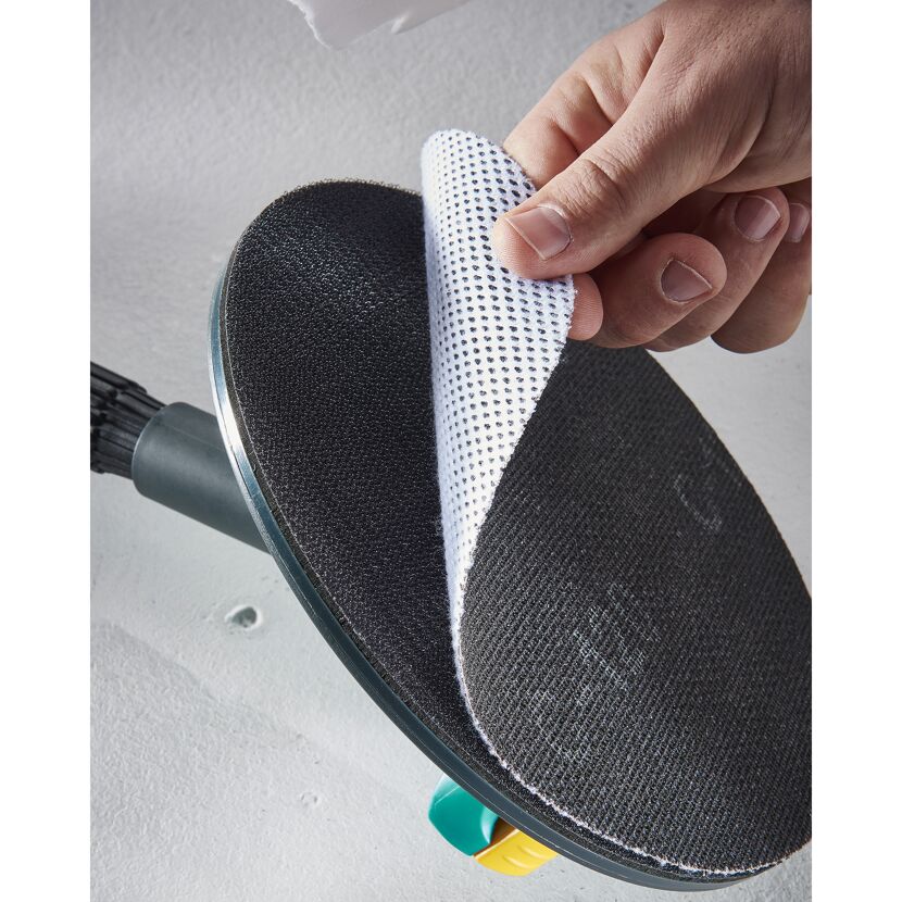 Hand hebt Schleifpapier von einem Rundschleifer ab