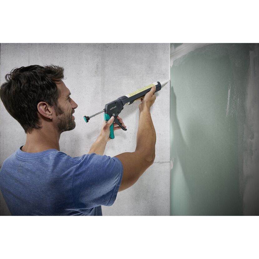 Person verwendet Kartuschenpresse zum Verfugen einer Wand