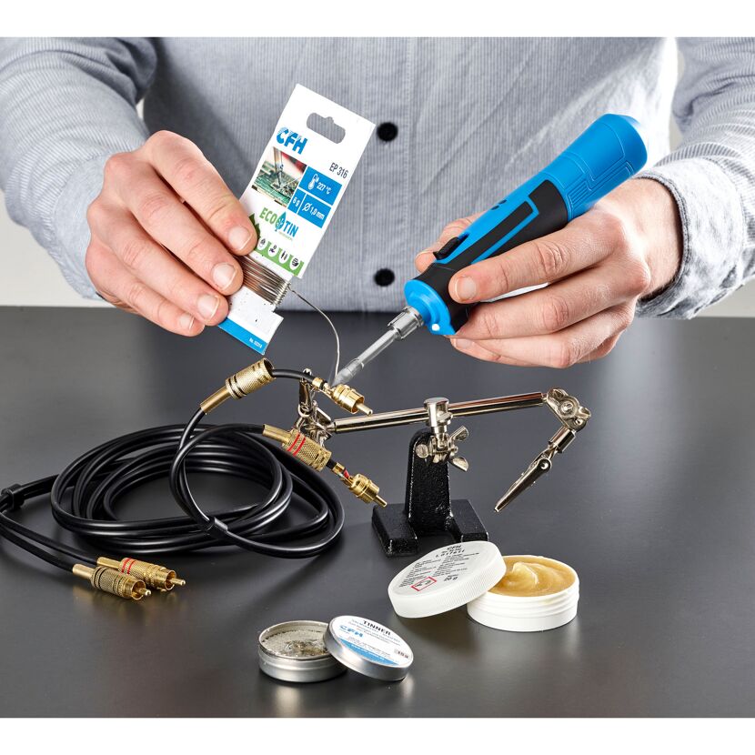 Person lötet Kabel mit Lötkolben und Lötzinn.