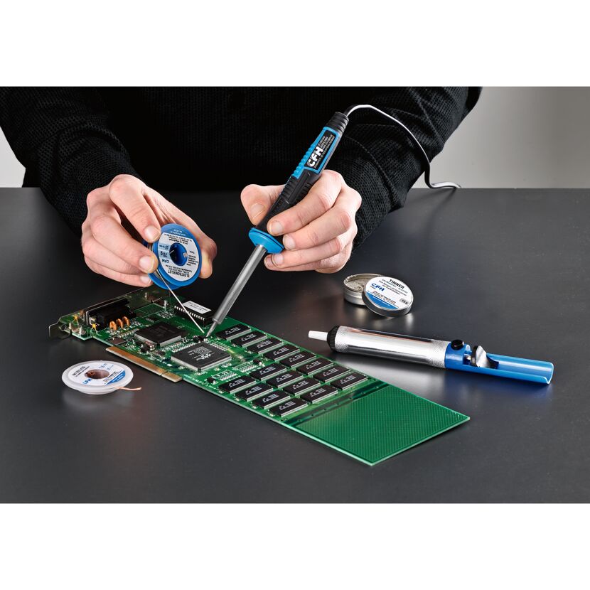 Person lötet eine Platine mit einem Lötkolben.