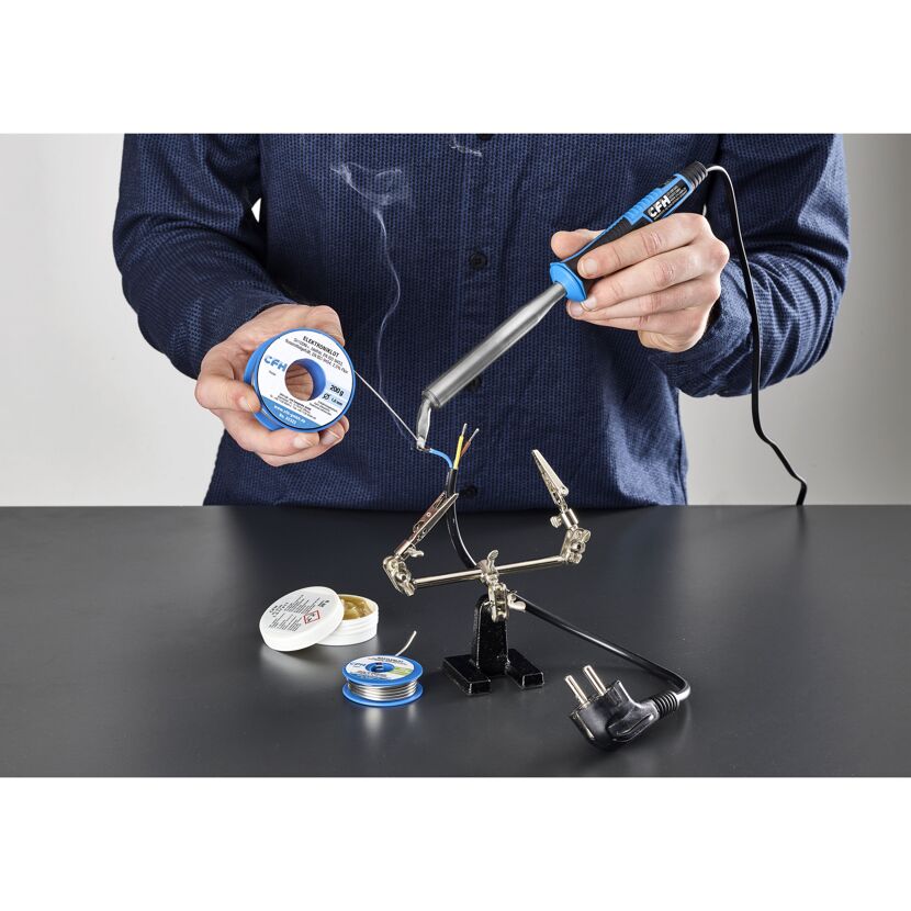 Person lötet Kabel mit Lötkolben.