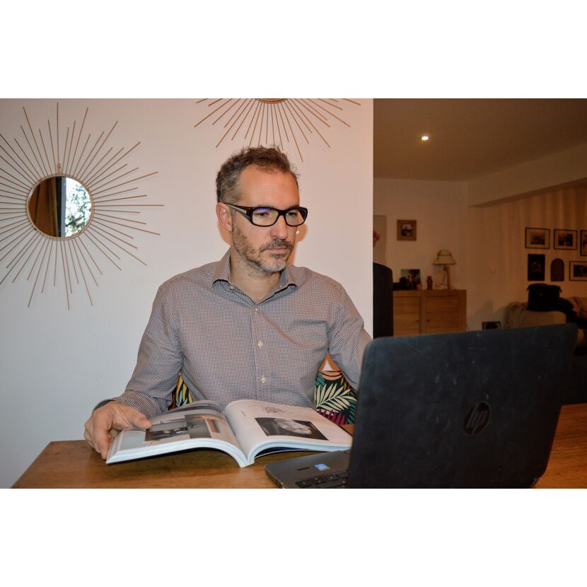 Person liest Buch und arbeitet am Laptop
