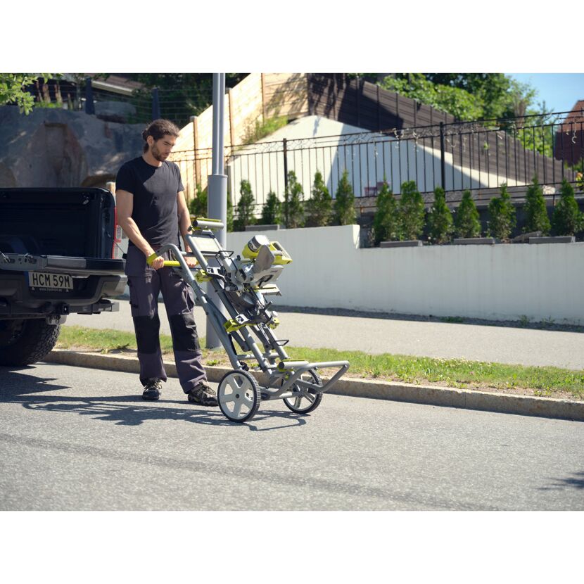 Person transportiert eine Kappsäge auf einem Untergestell.