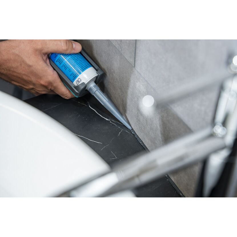 Person verwendet Dichtmittel im Badezimmer