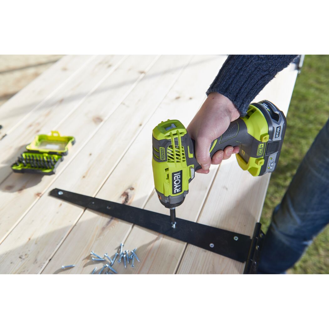 Person verschraubt Holzbrett mit RYOBI Akku-Schlagschrauber.