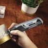 Person graviert mit dem Dremel Lite ein Objekt.