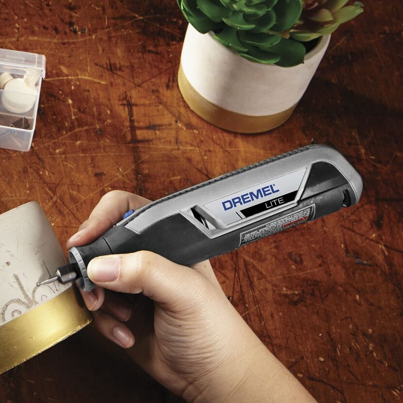 Person graviert mit dem Dremel Lite ein Objekt.