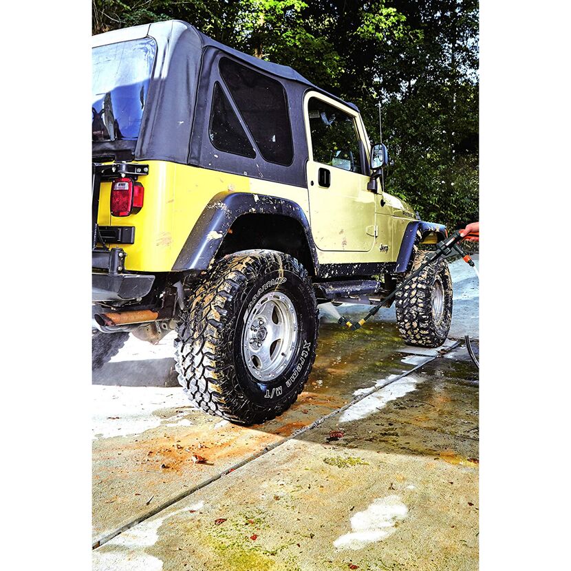 Person reinigt einen gelben Jeep mit einem Hochdruckreiniger.