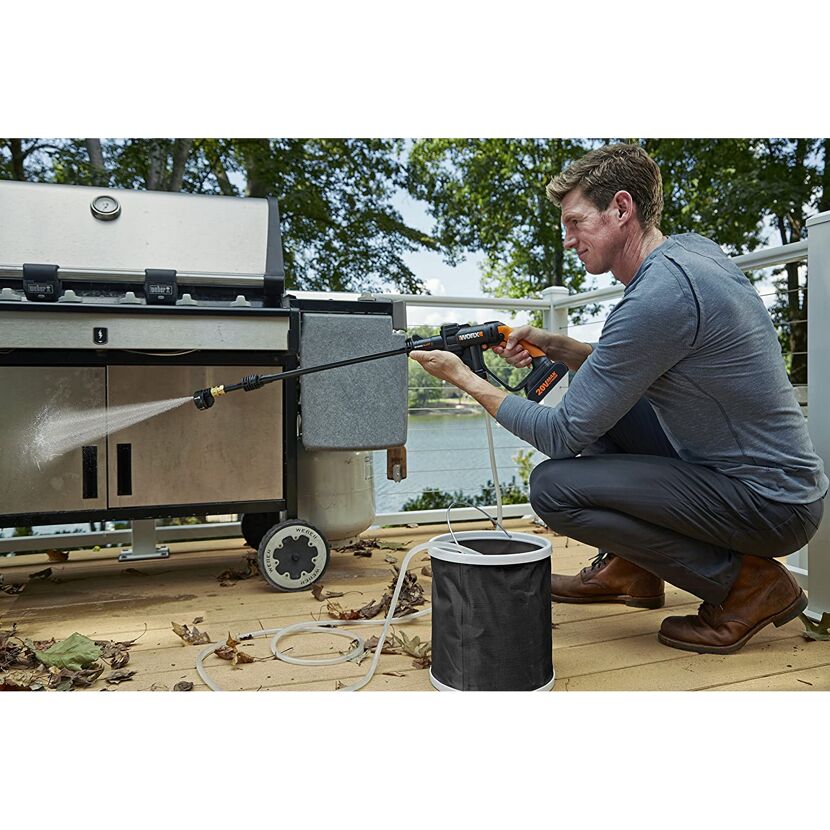 Person reinigt einen Grill mit einem Hochdruckreiniger.
