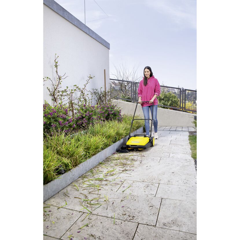 Person kehrt Laub mit Kehrmaschine.