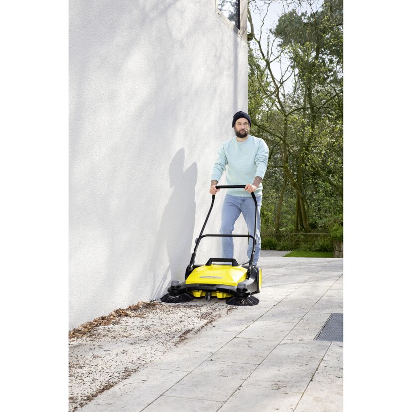 Person kehrt Laub mit einer Kehrmaschine
