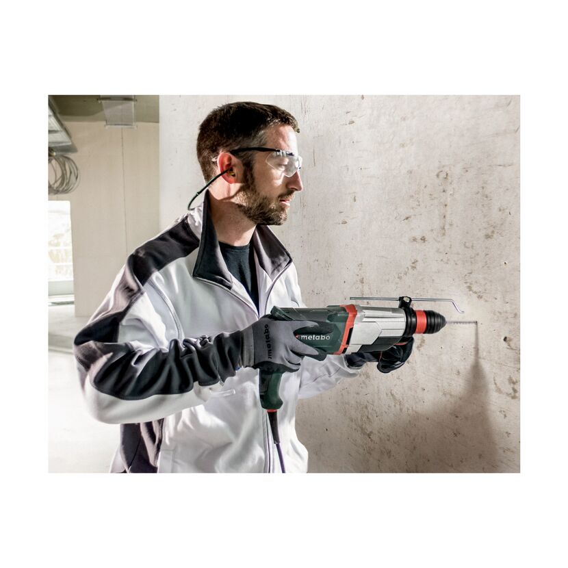 Person bohrt mit einem Kombihammer in eine Betonwand.