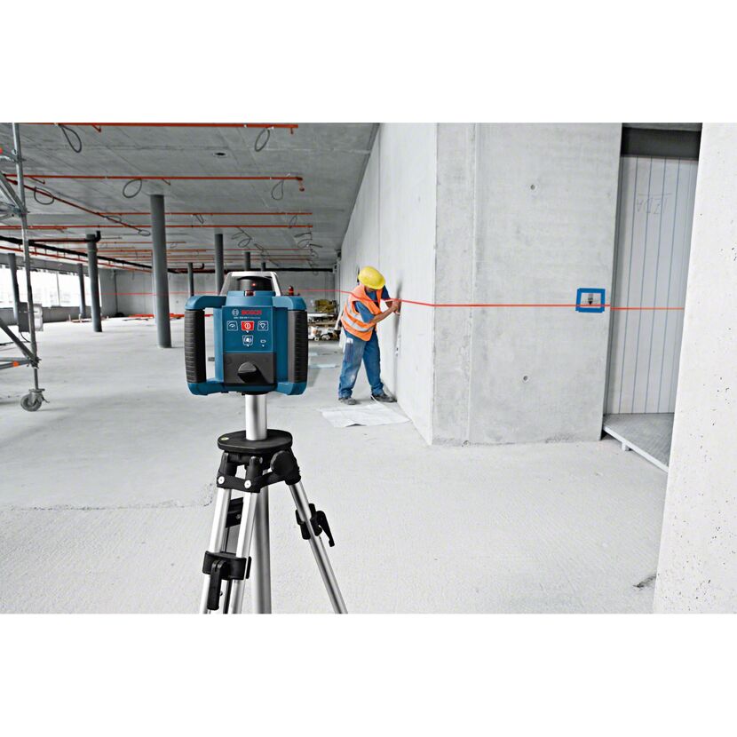 Rotationslaser auf Stativ, Person verwendet ihn an der Wand
