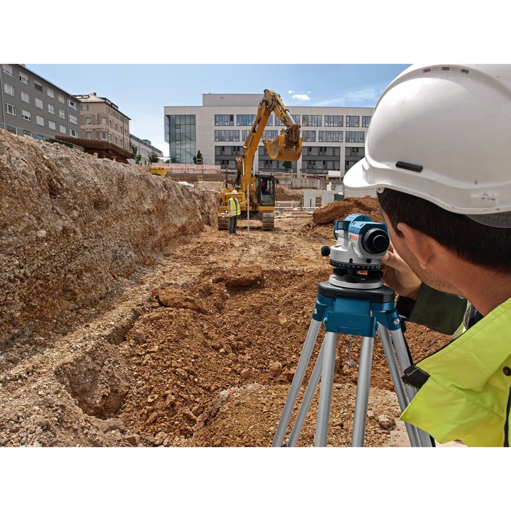 Person mit Nivelliergerät auf Baustelle