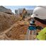 Person mit Nivelliergerät auf Baustelle